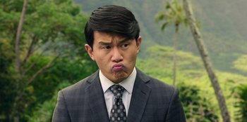 Movie still from “Vacation Friends 2” (2023), directed by Clay Tarver – A man in a suit and tie making a funny face; Close Up shot, Over the shoulder angle