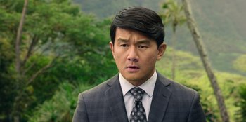 Movie still from “Vacation Friends 2” (2023), directed by Clay Tarver – A person wearing a suit and tie; Close Up shot, Over the shoulder angle