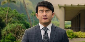 Movie still from “Vacation Friends 2” (2023), directed by Clay Tarver – A person wearing a suit and tie; Close Up shot, Over the shoulder angle