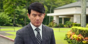 Movie still from “Vacation Friends 2” (2023), directed by Clay Tarver – A man in a suit and tie standing in front of a house; Close Up shot, Over the shoulder angle