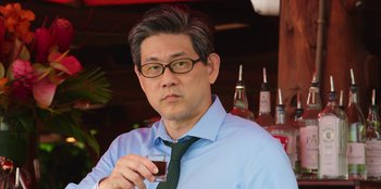 Movie still from “Vacation Friends 2” (2023), directed by Clay Tarver – A person holding a glass of wine; Close Up shot, Over the shoulder angle