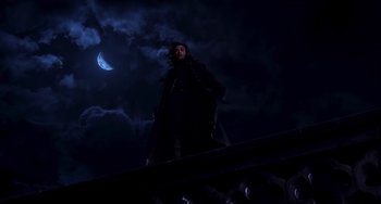 Movie still from “Van Helsing” (2004), directed by Stephen Sommers – A man standing on top of a building under a moon; Wide shot, Low angle