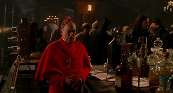 Movie still from “Van Helsing” (2004), directed by Stephen Sommers – A man wearing a red robe and a red hat; Medium shot, Over the shoulder angle