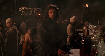 Movie still from “Van Helsing” (2004), directed by Stephen Sommers – A man holding a teapot in a dark room; Medium shot, Over the shoulder angle