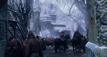 Movie still from “Van Helsing” (2004), directed by Stephen Sommers – A group of people riding horses near a building with smoke billowing from it; Wide shot, Low angle