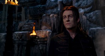 Movie still from “Van Helsing” (2004), directed by Stephen Sommers – A man with long hair standing in front of a stone wall; Medium shot, Over the shoulder angle