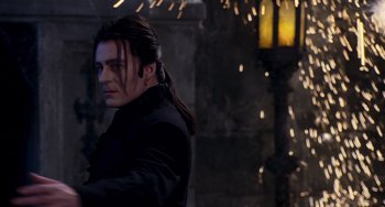 Movie still from “Van Helsing” (2004), directed by Stephen Sommers – A man with long black hair standing next to a lamp post; Medium shot, Over the shoulder angle