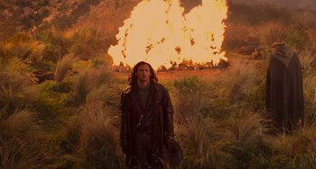 Movie still from “Van Helsing” (2004), directed by Stephen Sommers – A man standing in front of an exploding fire; Wide shot, Over the shoulder angle