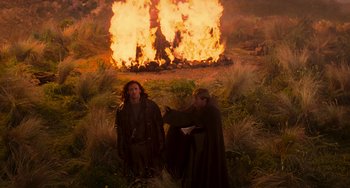 Movie still from “Van Helsing” (2004), directed by Stephen Sommers – Two men in medieval garb standing in front of a fire; Wide shot, High angle