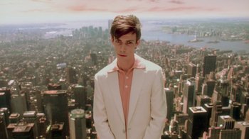 Movie still from “Vanilla Sky” (2001), directed by Cameron Crowe – A man in a white suit standing in front of a city; Medium shot, Low angle