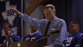 Movie still from “Varsity Blues” (1999), directed by Brian Robbins – An older man in a blue shirt is giving a speech; Medium shot, Low angle