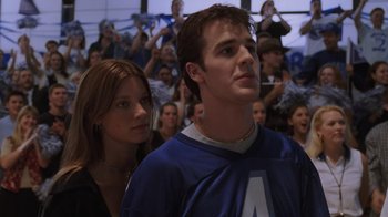 Movie still from “Varsity Blues” (1999), directed by Brian Robbins – A man and a woman are standing in front of a group of people; Close Up shot, Low angle
