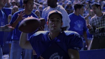 Movie still from “Varsity Blues” (1999), directed by Brian Robbins – A football player in the middle of a crowd of people; Medium shot, Low angle