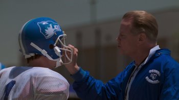 Movie still from “Varsity Blues” (1999), directed by Brian Robbins – A man putting a helmet on another man's face; Close Up shot, Over the shoulder angle