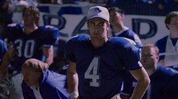 Movie still from “Varsity Blues” (1999), directed by Brian Robbins – A football player in a blue uniform and a white hat; Medium shot, Over the shoulder angle