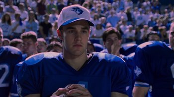 Movie still from “Varsity Blues” (1999), directed by Brian Robbins – A man in a football jersey and a hat is holding a ball; Close Up shot, Over the shoulder angle