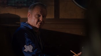 Movie still from “Varsity Blues” (1999), directed by Brian Robbins – A man in a blue jacket is holding a pencil; Medium shot, Over the shoulder angle