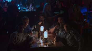 Movie still from “Varsity Blues” (1999), directed by Brian Robbins – A group of people sitting at a table in a bar; Wide shot, High angle