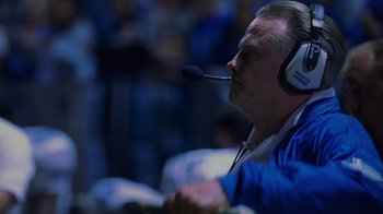 Movie still from “Varsity Blues” (1999), directed by Brian Robbins – An older man with a headset is sitting in a room; Close Up shot, Low angle