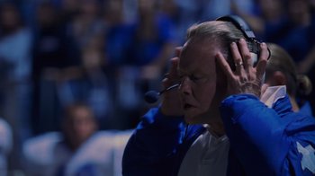 Movie still from “Varsity Blues” (1999), directed by Brian Robbins – An older man is holding a microphone in his ear; Close Up shot, Low angle