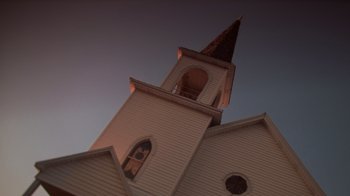 Movie still from “Varsity Blues” (1999), directed by Brian Robbins – A church steeple with a steeple that has a clock at the top of it; Extreme Wide shot, Low angle