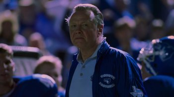 Movie still from “Varsity Blues” (1999), directed by Brian Robbins – An older man in a blue jacket stands in front of a crowd; Close Up shot, Low angle