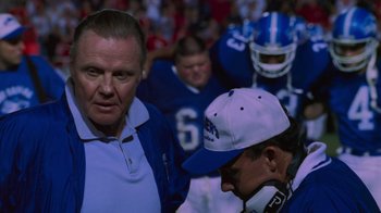 Movie still from “Varsity Blues” (1999), directed by Brian Robbins – A group of men standing next to each other on a football field; Medium shot, Low angle
