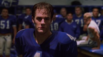 Movie still from “Varsity Blues” (1999), directed by Brian Robbins – A football player in a blue uniform is looking into the camera; Close Up shot, Low angle