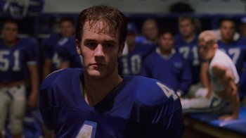 Movie still from “Varsity Blues” (1999), directed by Brian Robbins – A football player in a blue uniform in front of a group of players; Close Up shot, Low angle