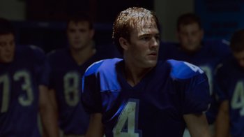 Movie still from “Varsity Blues” (1999), directed by Brian Robbins – A group of young men standing next to each other on top of a football field; Close Up shot, Low angle