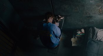 Movie still from “Venom: Let There Be Carnage” (2021), directed by Andy Serkis – A person sitting on a chair in a dark room; Medium shot, Overhead angle