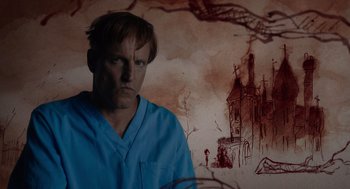 Movie still from “Venom: Let There Be Carnage” (2021), directed by Andy Serkis – A man standing in front of an image of a castle; Close Up shot, Low angle