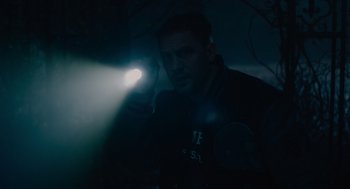 Movie still from “Venom: Let There Be Carnage” (2021), directed by Andy Serkis – A man holding a flashlight in a dark room; Close Up shot, High angle