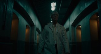 Movie still from “Venom: Let There Be Carnage” (2021), directed by Andy Serkis – A woman in a white lab coat standing in a dark hallway; Medium shot, Low angle