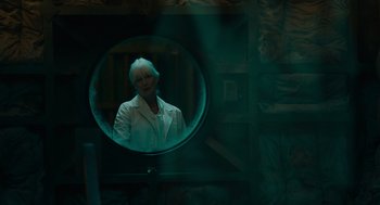 Movie still from “Venom: Let There Be Carnage” (2021), directed by Andy Serkis – A woman in a white jacket is reflected in a round mirror; Medium shot, Low angle