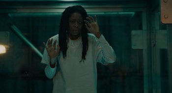 Movie still from “Venom: Let There Be Carnage” (2021), directed by Andy Serkis – A man with dreadlocks standing in front of a window; Medium shot, Low angle