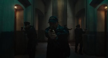 Movie still from “Venom: Let There Be Carnage” (2021), directed by Andy Serkis – A man holding a bottle of beer in a dark room; Medium shot, Low angle