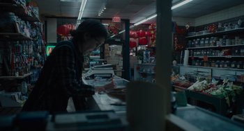 Movie still from “Venom: Let There Be Carnage” (2021), directed by Andy Serkis – A person standing in a store looking at papers on a counter; Medium shot, Low angle