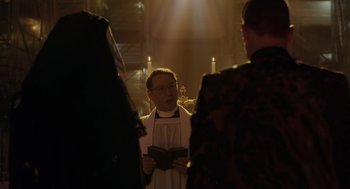 Movie still from “Venom: Let There Be Carnage” (2021), directed by Andy Serkis – A priest is holding a bible in front of a group of people; Medium shot, Low angle