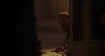 Movie still from “Venom: Let There Be Carnage” (2021), directed by Andy Serkis – A man sitting on the ground looking at something; Medium shot, Low angle