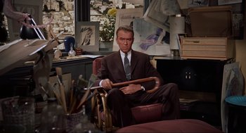 Movie still from “Vertigo” (1958), directed by Alfred Hitchcock – A man in a suit and tie holding an object in his hands; Medium shot, High angle