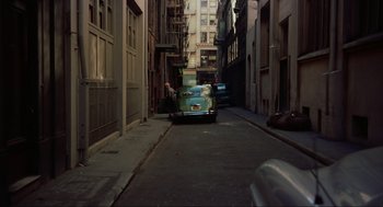 Movie still from “Vertigo” (1958), directed by Alfred Hitchcock – An old car is parked in the middle of a narrow street; Extreme Wide shot, High angle