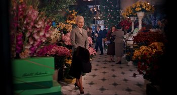 Movie still from “Vertigo” (1958), directed by Alfred Hitchcock – A woman in a gray suit is holding a black bag; Wide shot, High angle