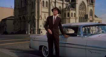 Movie still from “Vertigo” (1958), directed by Alfred Hitchcock – A man standing next to an old car in front of a church; Wide shot, Low angle