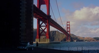 Movie still from “Vertigo” (1958), directed by Alfred Hitchcock – A person standing next to a body of water near a bridge; Extreme Wide shot, High angle