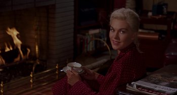 Movie still from “Vertigo” (1958), directed by Alfred Hitchcock – A woman sitting in front of a fireplace holding a cup; Medium shot, High angle