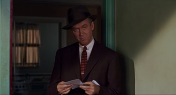 Movie still from “Vertigo” (1958), directed by Alfred Hitchcock – A man in a suit and hat holding a piece of paper; Close Up shot, Over the shoulder angle