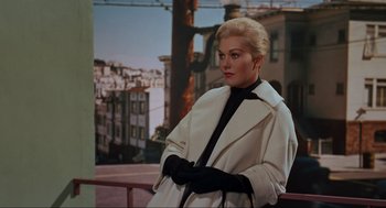 Movie still from “Vertigo” (1958), directed by Alfred Hitchcock – A beautiful blonde woman wearing a white coat and black gloves; Medium shot, Low angle
