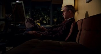 Movie still from “Vertigo” (1958), directed by Alfred Hitchcock – A man sitting on a couch looking at a laptop computer; Wide shot, High angle