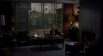 Movie still from “Vertigo” (1958), directed by Alfred Hitchcock – A man sitting on a couch in front of a window; Wide shot, High angle